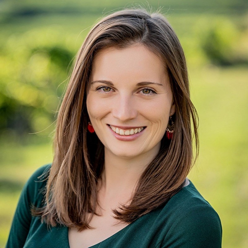 Melanie, die Eigentümerin des Hauses, vor grüner Hügellandschaft